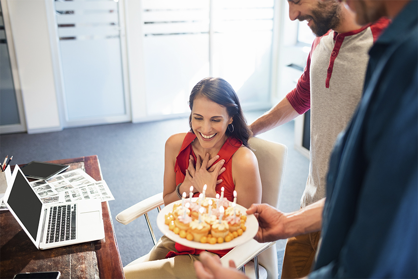 Frau wird im Büro mit Kuchen überrascht