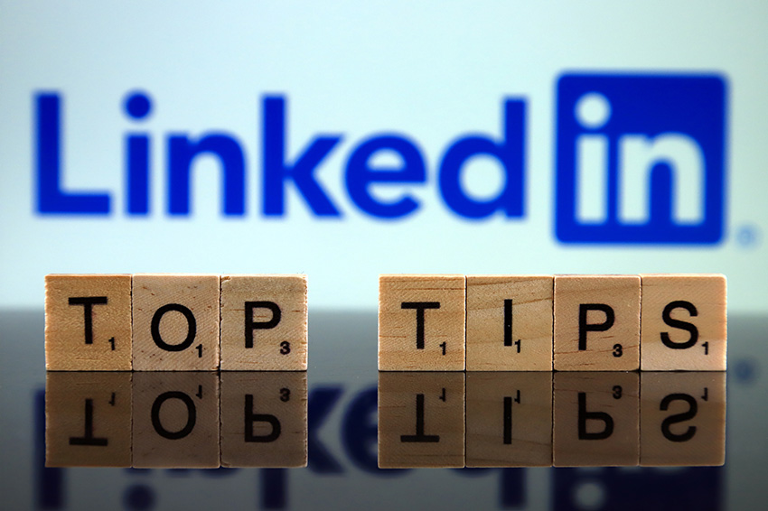 Das Titelbild des Blogs über relevanten Content für LinkedIn zeigt das LinkedIn Logo und Holztafeln mit Buchstaben drauf, die das Wort Top Tips bilden.